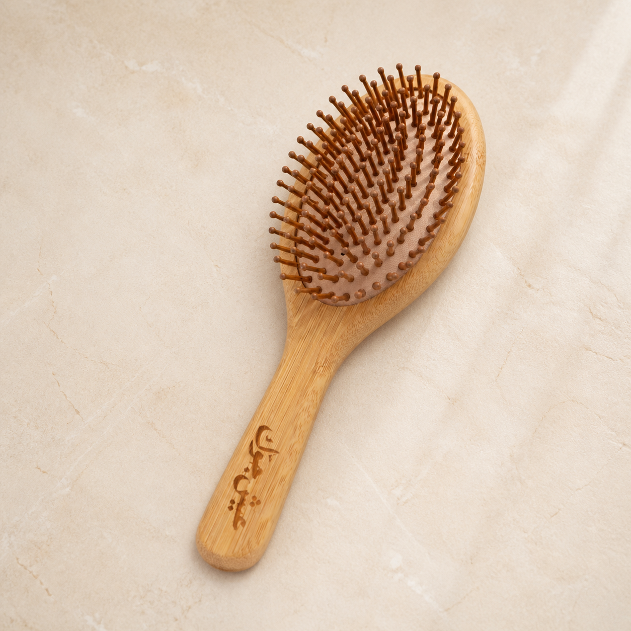 Eco-Friendly Bamboo Hair Brush on a warm ivory mineral surface
