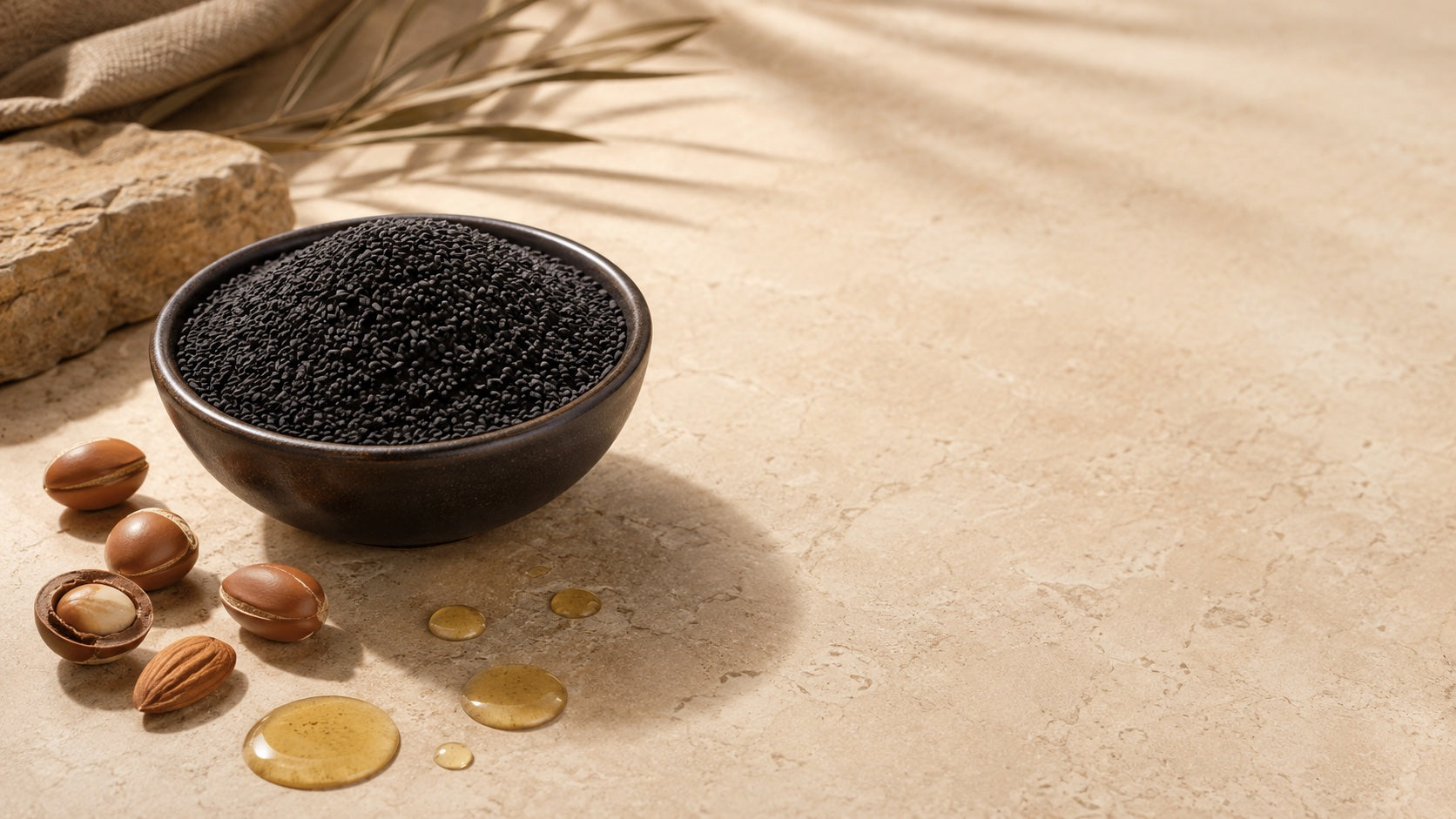 Black seed in a bowl with oil drops and almond accents